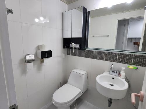 ein weißes Bad mit einem WC und einem Waschbecken in der Unterkunft Welcome to Jejubi house in Jeju-do