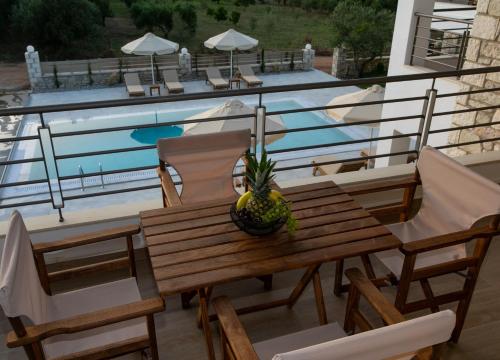 a wooden table and chairs next to a swimming pool at Michelangelo suites and apartments in Valanidorachi