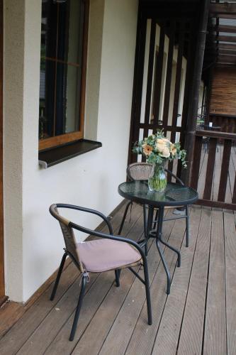 a table and chair on a porch with a vase of flowers at Resort Lesní Lázně in Zvánovice
