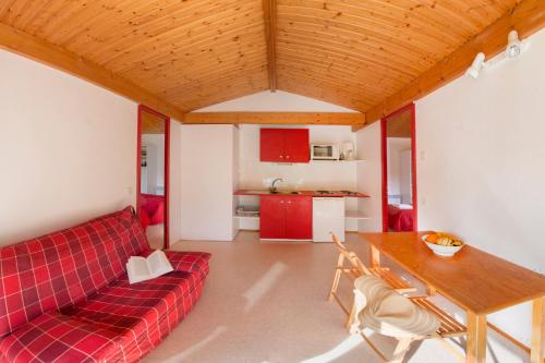 un salon avec un canapé rouge et une table dans l'établissement LE HAMEAU DES ETOILES, à Fleurance