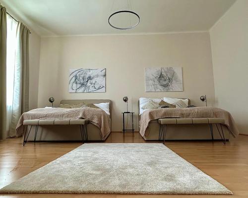 two beds in a white room with a rug at Stylish Apartment, next to Schloss Belvedere in Vienna