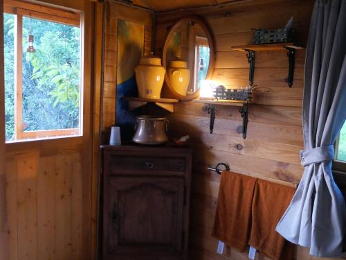 Habitación con pared de madera, espejo y lavabo. en Maison Dougnac La Chamane, en Fleurance