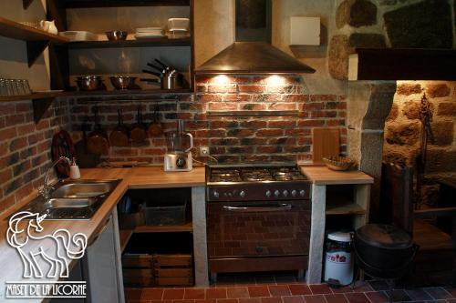 - une cuisine avec une cuisinière et un mur en briques dans l'établissement Maset de la Licorne, à Nedde