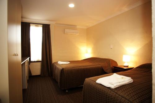 a hotel room with two beds and a television at Prince of Wales Hotel, Bunbury in Bunbury