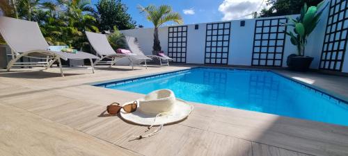 a swimming pool with chairs and a hat next to a tub at charmante maison avec piscine, idéale famille in Saint-Pierre