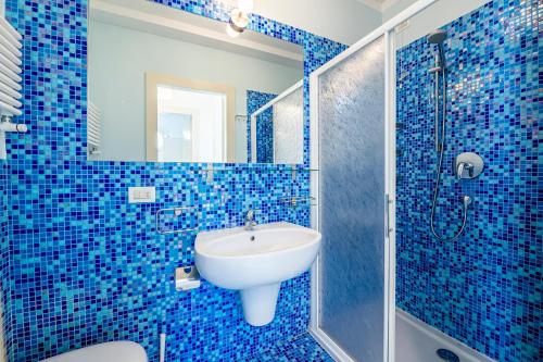 W wyłożonej niebieskimi kafelkami łazience znajduje się umywalka i prysznic. w obiekcie [Fronte Mare]-Sweet Home-[Free Parking] w mieście Marina di Pisa