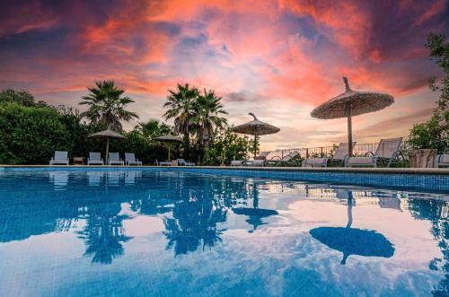 una piscina con sombrillas y una puesta de sol en Finca es Rafal, Agroturisme, en Montuiri