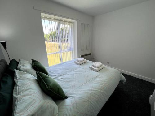 a bedroom with a bed with green pillows and a window at Marina Princes Reach 2 in Penwortham