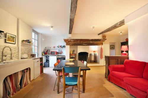 a kitchen and living room with a red couch and a table at Château de Fontanas, le Puits in Grisolles