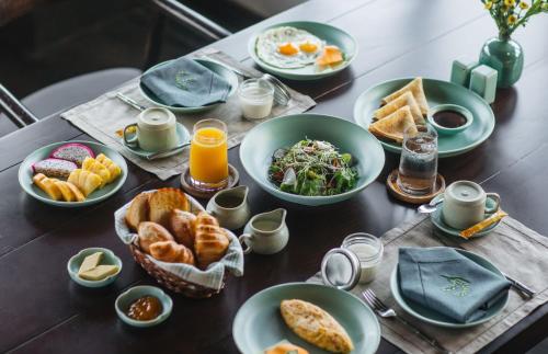 een tafel met borden ontbijtproducten en jus d'orange bij Aravinda Resort Ninh Binh in Ninh Binh