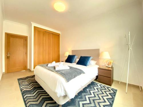 a bedroom with a large white bed with blue pillows at Deluxe 2 Bedroom Flat - BeachFront - Praia Del Rey in Amoreira