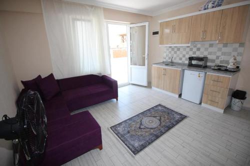 Vera Apart Otel في مرمرة: غرفة معيشة مع أريكة أرجوانية ومطبخ