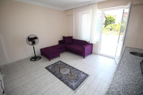 a living room with a purple couch and a fan at Vera Apart Otel in Marmara
