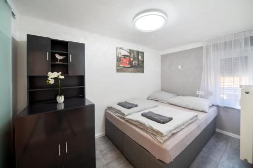 a bedroom with a large bed with a dresser at Centroom Pécs Apartman in Pécs