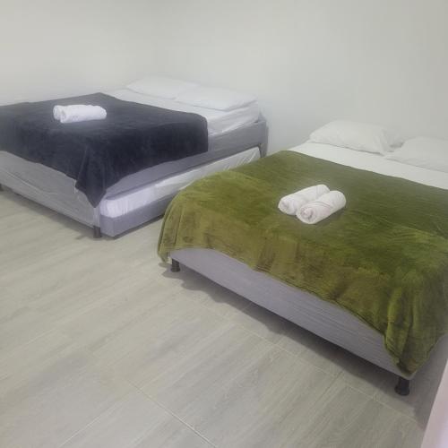 2 camas con mantas verdes y toallas. en FINCA HOTEL EL TURPIAL, en Quimbaya