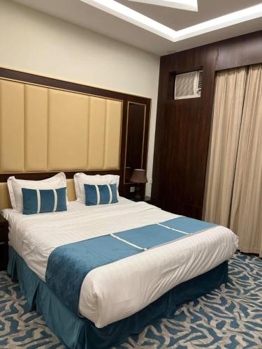 a hotel room with a large bed with blue pillows at شقق هدوء الليالي للشقق المخدومة in Khamis Mushayt