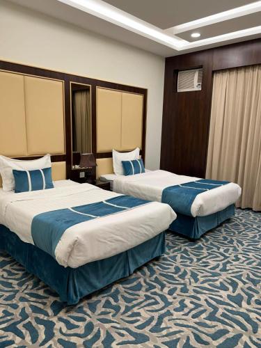 a hotel room with two beds with blue sheets at شقق هدوء الليالي للشقق المخدومة in Khamis Mushayt