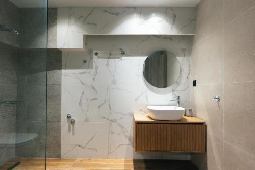 a bathroom with a sink and a shower with a mirror at Isla Villas & Suites in Balíon