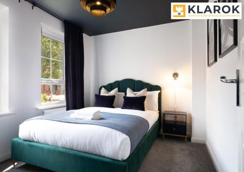 a bedroom with a large bed with a green headboard at Four Bedroom Semi Detached House By Klarok Accommodation Peterborough With Free Parking & Garden in Peterborough