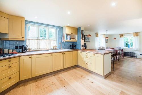 a kitchen with yellow cabinets and a wooden floor at The Old Forge, Great Glemham in Great Glemham