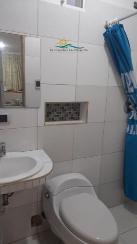 La salle de bains est pourvue de toilettes blanches et d'un lavabo. dans l'établissement Posada Villa Mayo Apartamento Familiar a 5 Min de Playa Parguito, à Paraguchi