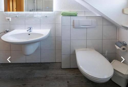 a white bathroom with a sink and a toilet at Lütten Uttied I in Norddeich