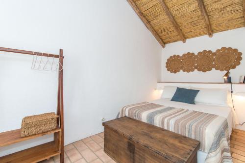 een slaapkamer met een bed en een houten tafel bij Casa Formosa - Serena Tradição in Santa Luzia