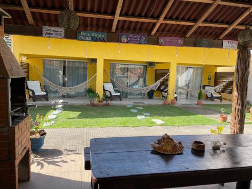 a patio with a table and hammocks in a house at Casa Temporada Suítes in Maragogi
