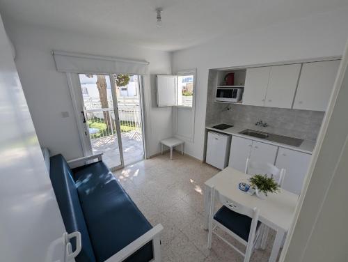 cocina con armarios blancos, mesa y comedor en Flisvos Beach Apartments en Protaras