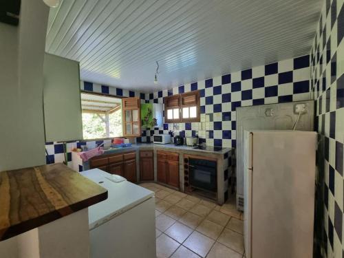a kitchen with a white refrigerator and a tile wall at location toussaint in Rivière-Pilote