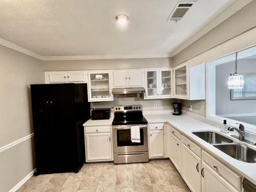 a kitchen with white cabinets and a black refrigerator at Ecstatic Town Home In Stone Mountain in Stone Mountain
