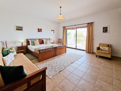 a bedroom with a bed and a living room with a couch at Villa Ninho do Mocho in Portimão