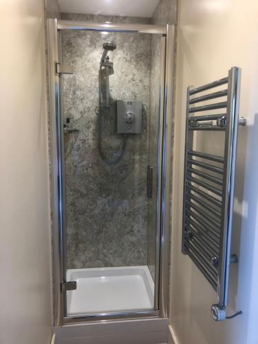 a shower with a glass door in a bathroom at SHEPHERDS HUT in Kent