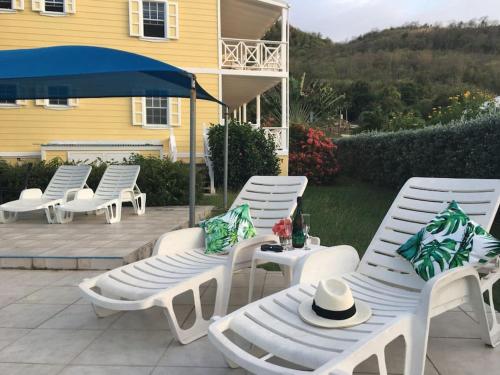 a group of white chairs and an umbrella on a patio at Palm breeze: sea view near Jolly Beach in Jolly Harbour
