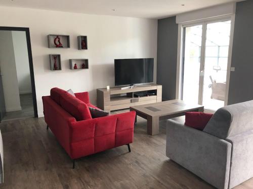 un soggiorno con 2 sedie rosse e una televisione di MAISON FAMILLE a Saint-Gervais