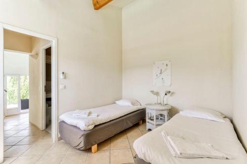 2 camas en una habitación con paredes blancas en Villa Syrah avec piscine privée chauffée à 25 km de la mer, en Coustouge