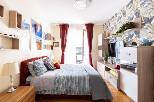 a small bedroom with a bed and a tv at Cozy apt 10 mins walk from Poetto + terrace in Cagliari