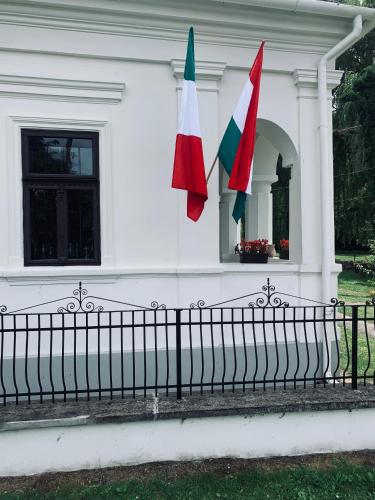 a white house with two flags on a fence at Agriturismo Villa Carlotta in Szilvásvárad