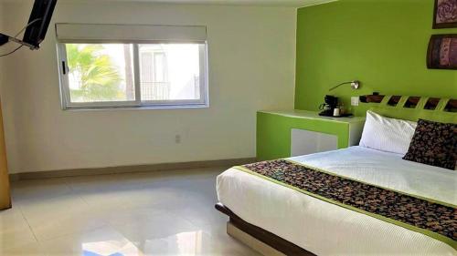 a green bedroom with a bed and a window at Seven Crown Express & Suites by Kavia in Cabo San Lucas