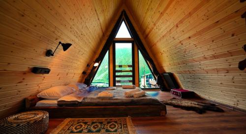 a bedroom with a bed in a room with a large window at Kazbegi Spa Resort Cottages in Stepantsminda