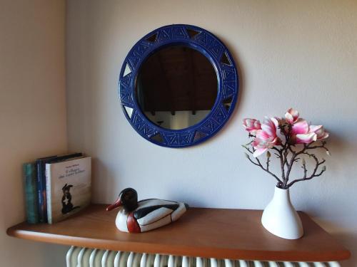 a shelf with a mirror and a duck and a vase with flowers at La Casa del Colibrì in Lecco