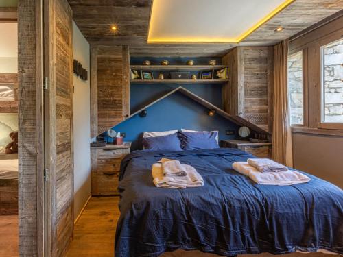 une chambre avec un grand lit bleu et des murs en bois dans l'établissement Appartement skis aux pieds avec parking et wifi au cœur de Val-d’Isère - FR-1-694-317, à Val dʼIsère