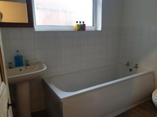 a white bathroom with a tub and a window at Large first floor flat walking distance to beach in Weston-super-Mare