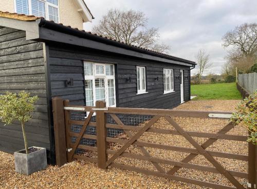 a wooden fence in front of a black shed at Near Woodbridge The Annexe Eyke Fantastic views with Dog secure Garden and Paddock in Eyke