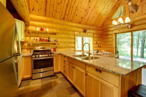 a kitchen with a stove and a sink in a log cabin at Secluded Log Cabin in NW Michigan Hot Tub and Deck in Evart