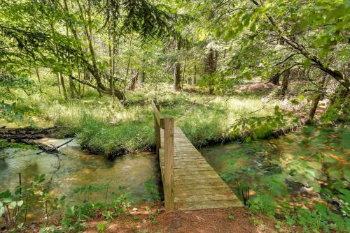 a wooden bridge over a stream in a forest at Secluded Log Cabin in NW Michigan Hot Tub and Deck in Evart