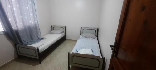 2 Einzelbetten in einem Zimmer mit Fenster in der Unterkunft Mini villa in Saidia 