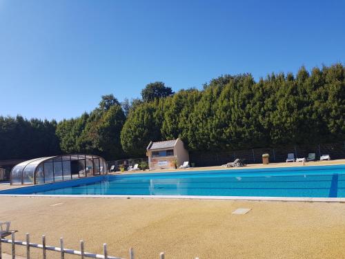 une grande piscine avec une maison et des arbres dans l'établissement Mobilhome 6 places dans camping 4* Finistère Sud, à Saint-Yvy