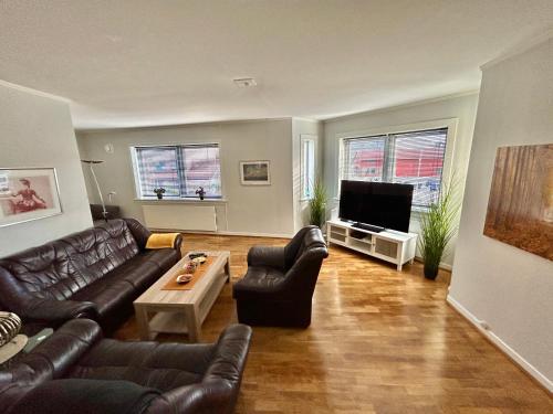 a living room with leather furniture and a flat screen tv at Gjestehuset Borggata 18 in Fredrikstad