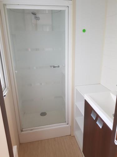 une salle de bain avec une douche avec une porte vitrée dans l'établissement Mobilhome 6 places dans camping 4* Finistère Sud, à Saint-Yvy